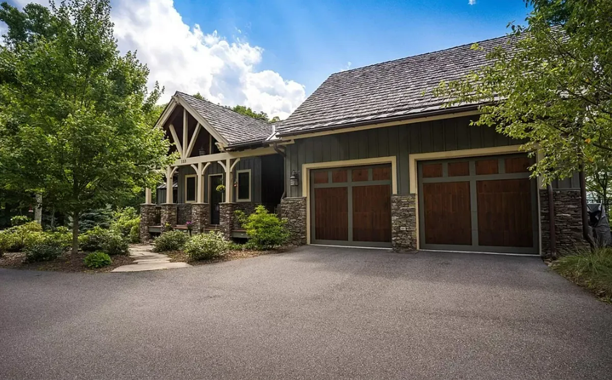 A welcoming front porch with stone accents and wooden garage doors, surrounded by natural landscaping. The space feels inviting, offering a sense of arrival and security typical of a well-maintained mountain community entrance.